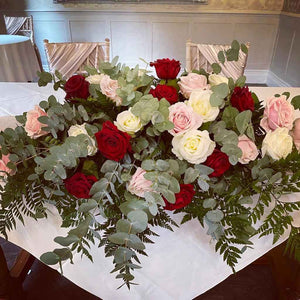 wedding flowers large rose head table arrangement with pinks reds and creams