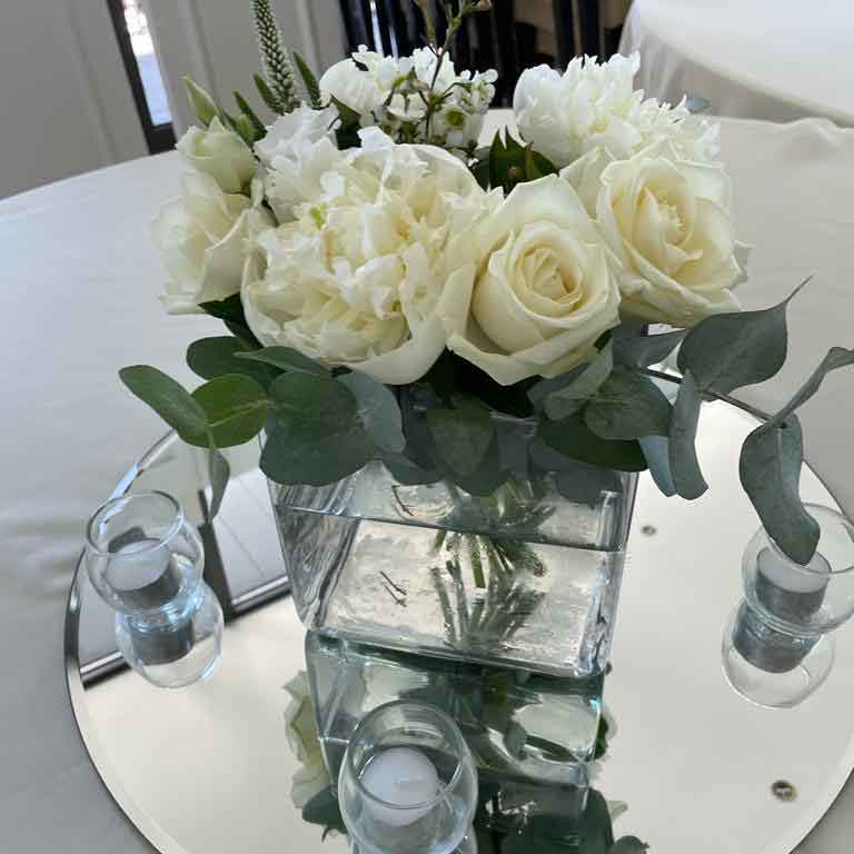 white wedding floral table arrangement with white roses and candles 